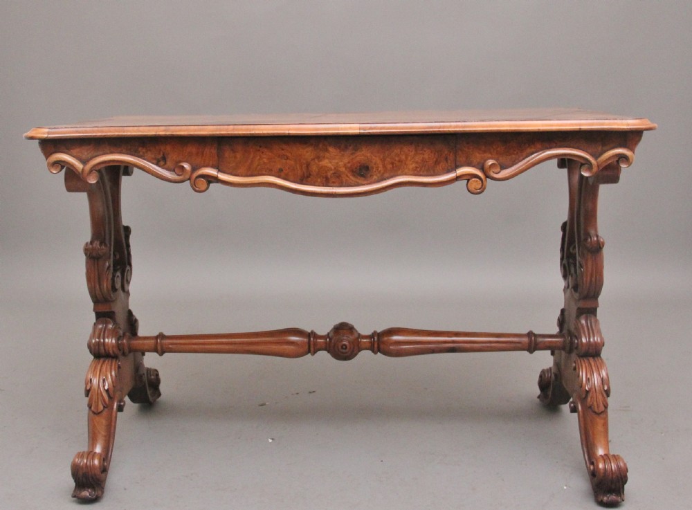 A 19th-century burr walnut centre table featuring a serpentine top and elaborate carved scroll supports joined by a turned stretcher. View III