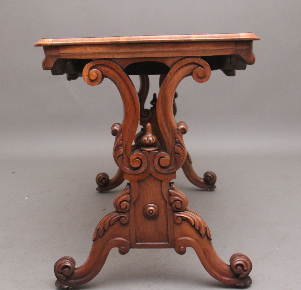 A 19th-century burr walnut centre table featuring a serpentine top and elaborate carved scroll supports joined by a turned stretcher. View VI