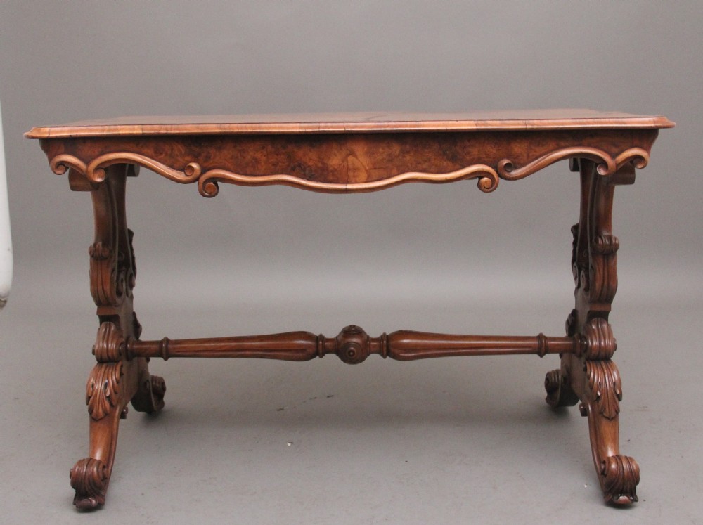 A 19th-century burr walnut centre table featuring a serpentine top and elaborate carved scroll supports joined by a turned stretcher. View VIII