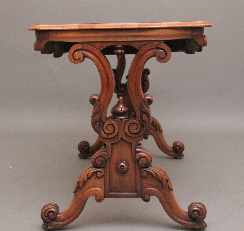 A 19th-century burr walnut centre table featuring a serpentine top and elaborate carved scroll supports joined by a turned stretcher. View IX