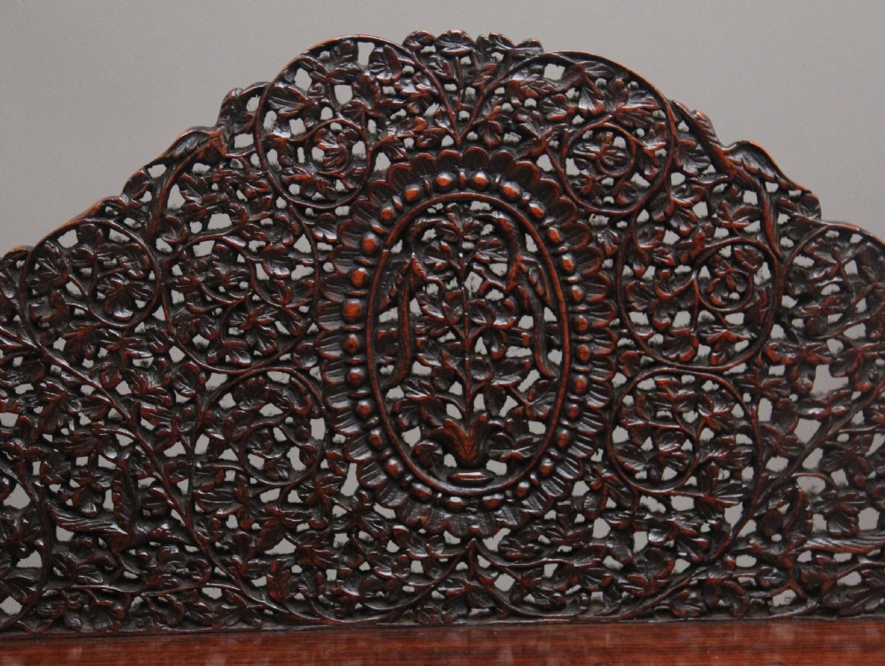 A 19th-century dark wood Anglo-Indian cabinet featuring intricate pierced floral carving, an arched panel door, and carved lion feet. View IV