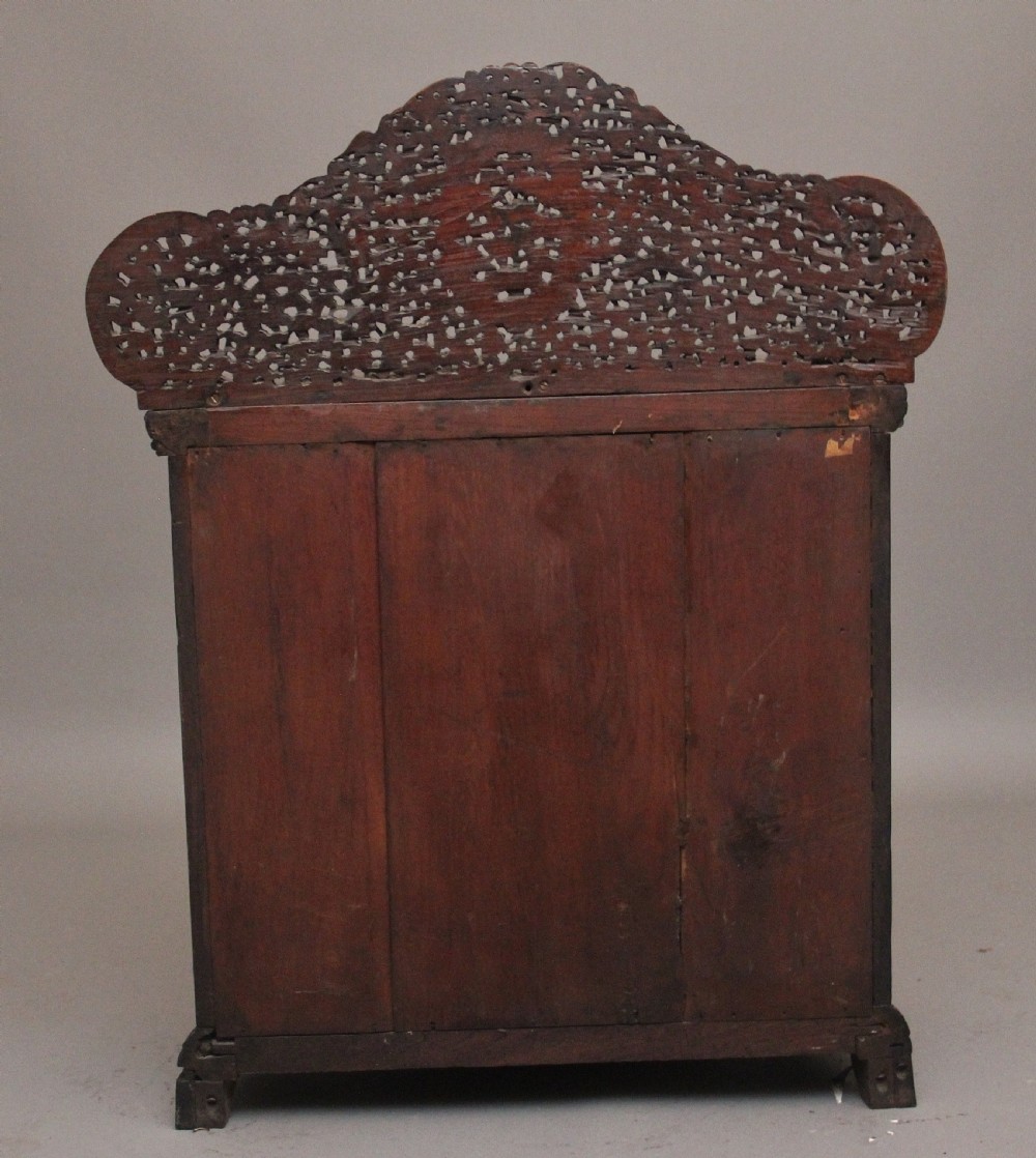 A 19th-century dark wood Anglo-Indian cabinet featuring intricate pierced floral carving, an arched panel door, and carved lion feet. View VII