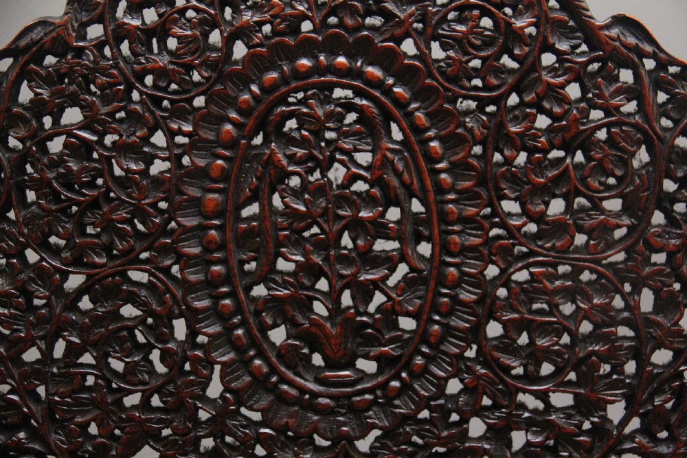 A 19th-century dark wood Anglo-Indian cabinet featuring intricate pierced floral carving, an arched panel door, and carved lion feet. View XVI