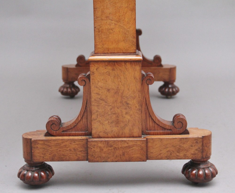 An early 19th-century pollard oak dumb waiter featuring three rectangular tiered shelves supported by upright pillars and a carved trestle base with lobed feet. View VI