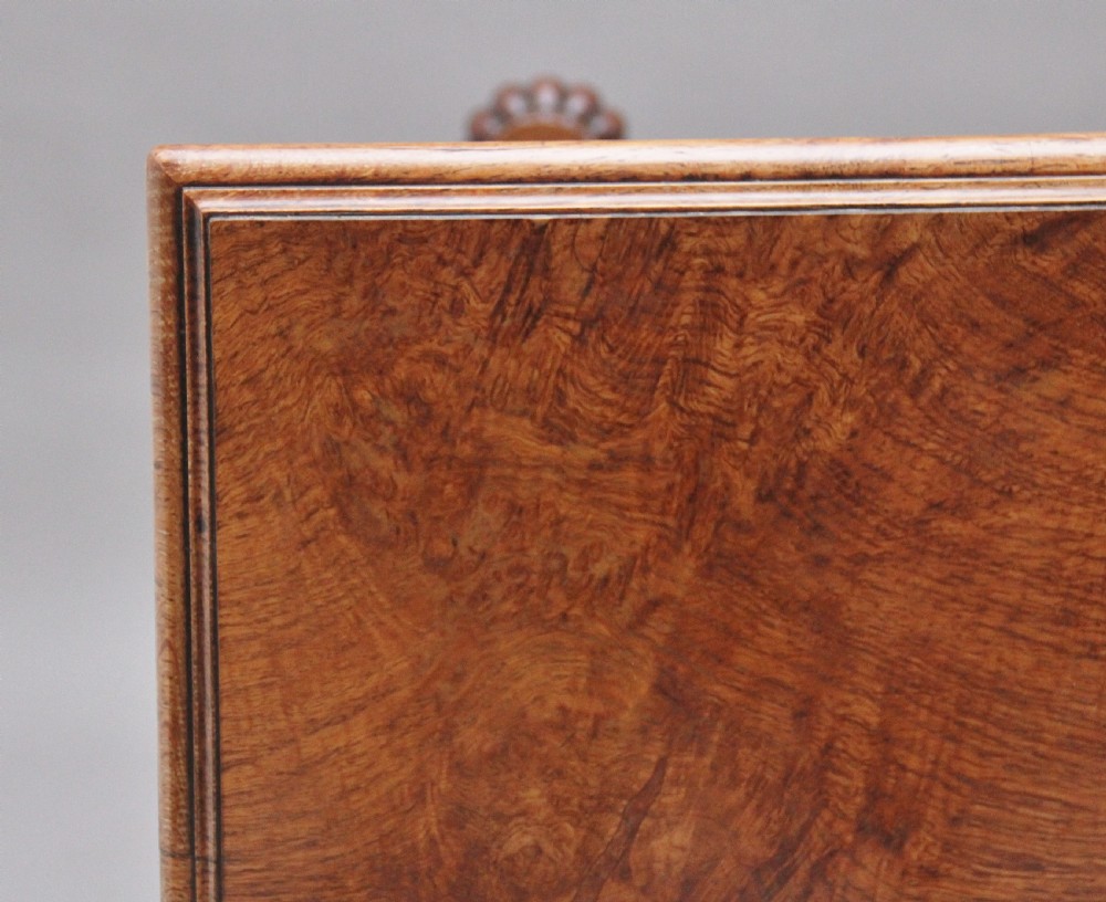 An early 19th-century pollard oak dumb waiter featuring three rectangular tiered shelves supported by upright pillars and a carved trestle base with lobed feet. View X