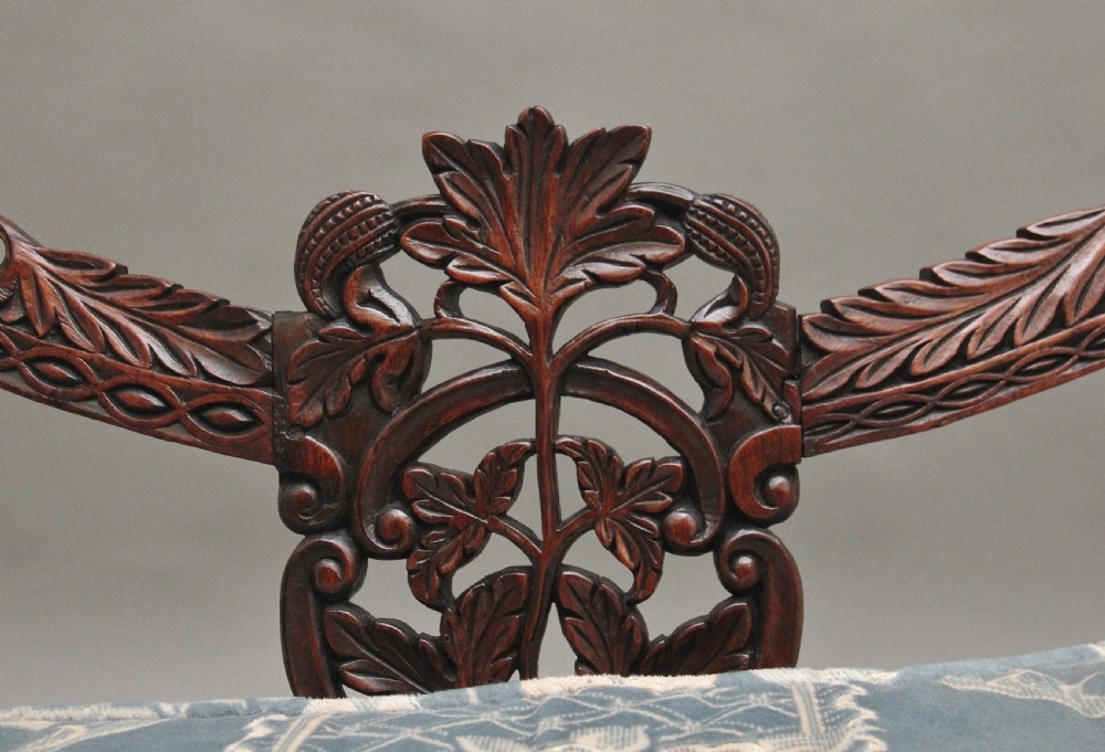 A 19th-century Anglo-Indian carved dark hardwood sofa featuring intricate foliage openwork, lion head armrests, and a patterned blue upholstered seat. View IX