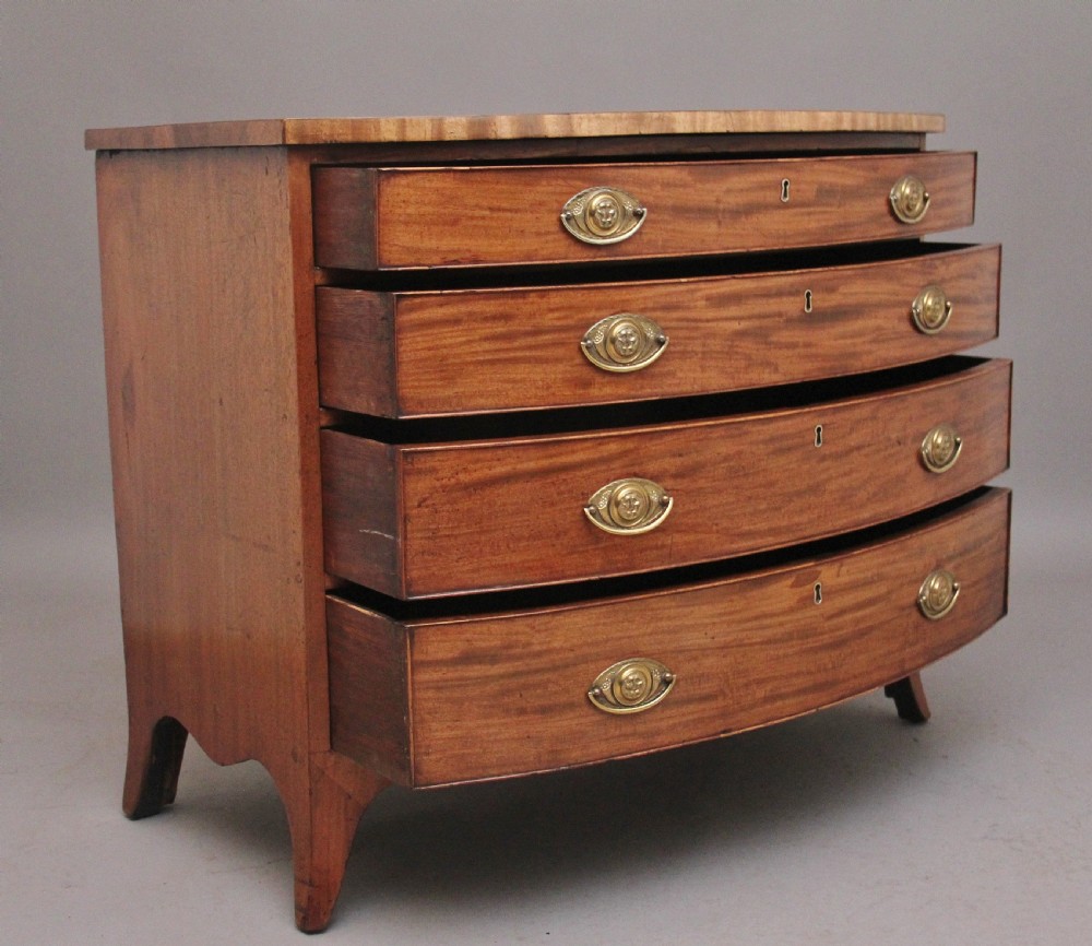 A nineteenth-century mahogany bowfront chest of drawers featuring four graduated drawers with oval brass handles and splayed feet. View III