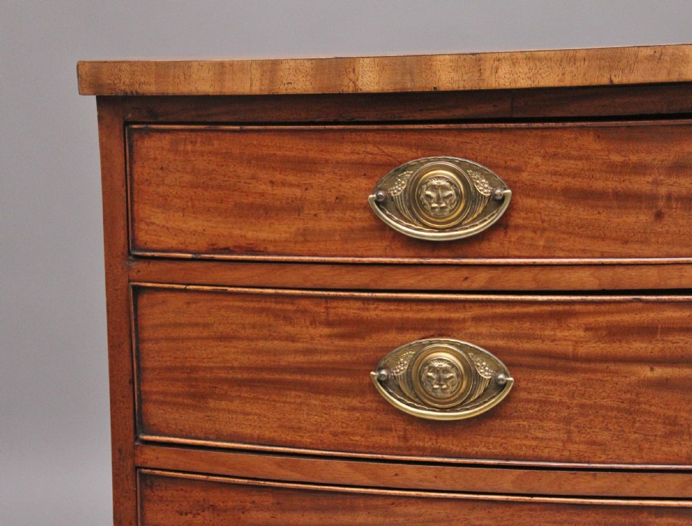 A nineteenth-century mahogany bowfront chest of drawers featuring four graduated drawers with oval brass handles and splayed feet. View VI
