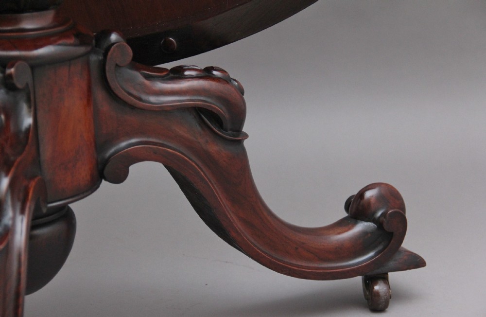 A 19th-century circular rosewood breakfast table displayed tilted upright on a carved tripod base with scroll feet. View VIII