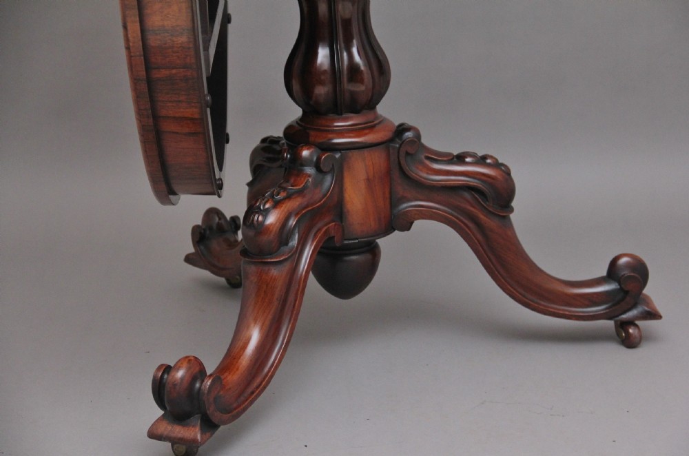 A 19th-century circular rosewood breakfast table displayed tilted upright on a carved tripod base with scroll feet. View IX