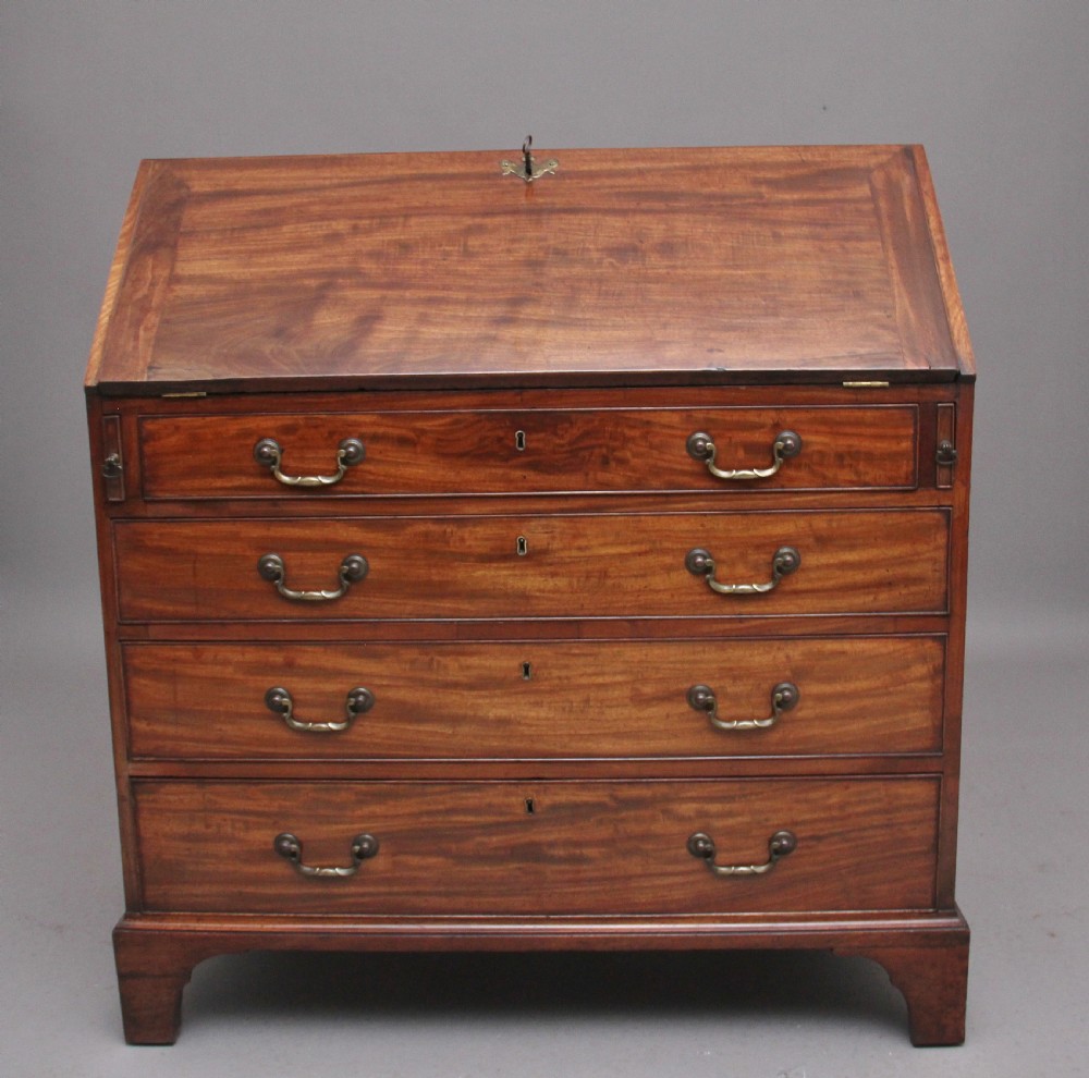 An eighteenth-century mahogany writing bureau featuring a slant-front slope above four graduated drawers with brass swan-neck handles and bracket feet.