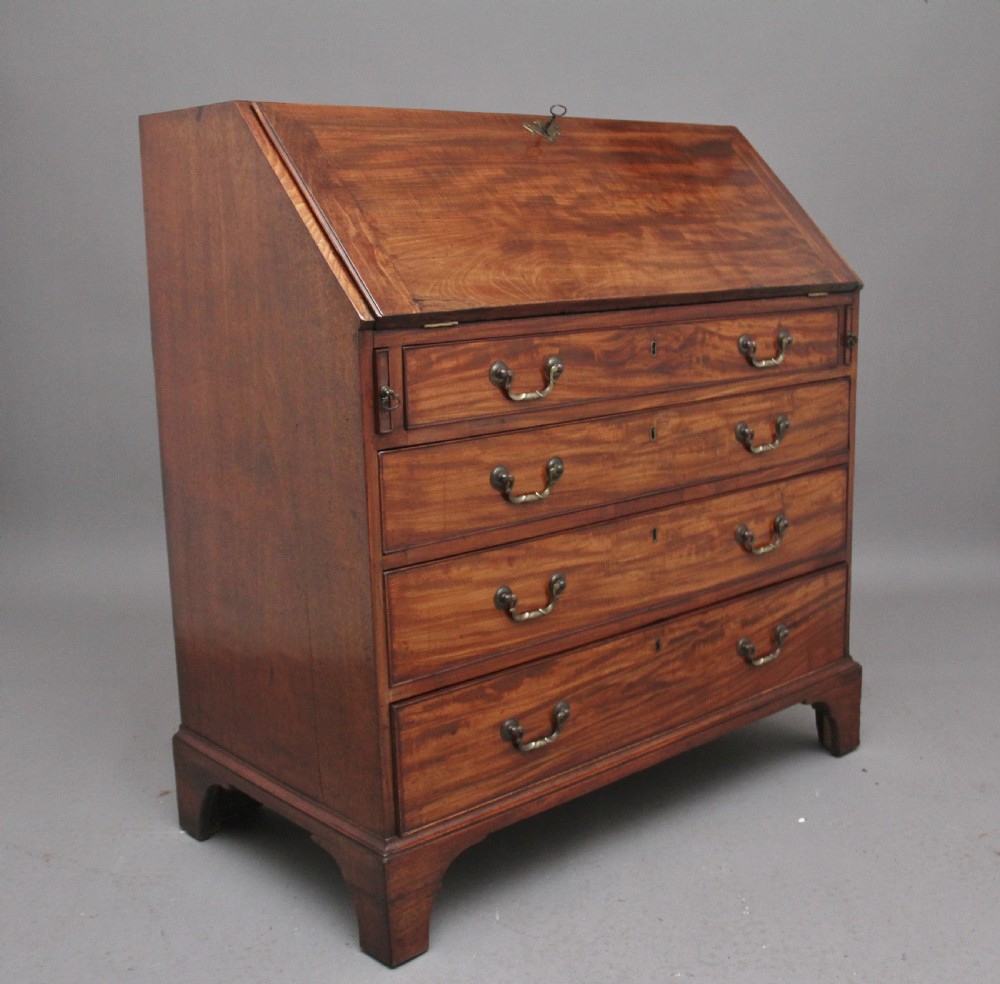 An eighteenth-century mahogany writing bureau featuring a slant-front slope above four graduated drawers with brass swan-neck handles and bracket feet. View V