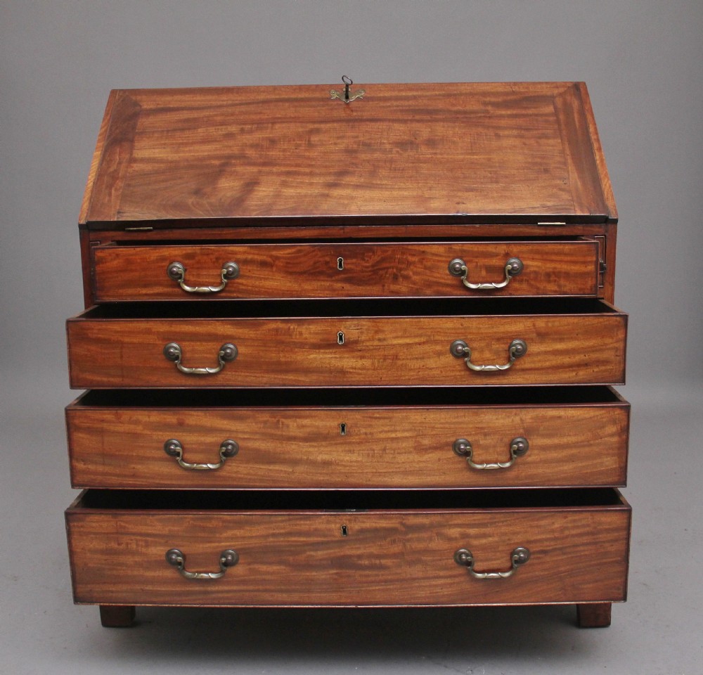 An eighteenth-century mahogany writing bureau featuring a slant-front slope above four graduated drawers with brass swan-neck handles and bracket feet. View VI