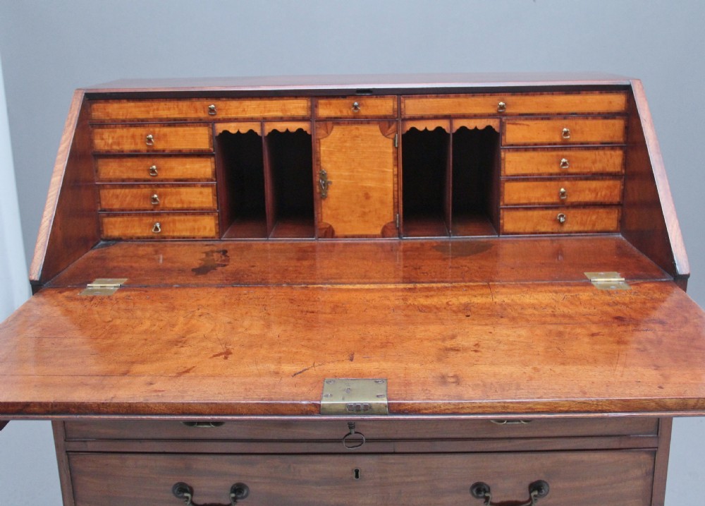 An eighteenth-century mahogany writing bureau featuring a slant-front slope above four graduated drawers with brass swan-neck handles and bracket feet. View IX