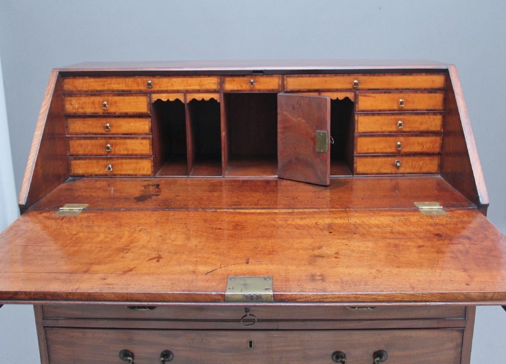 An eighteenth-century mahogany writing bureau featuring a slant-front slope above four graduated drawers with brass swan-neck handles and bracket feet. View X