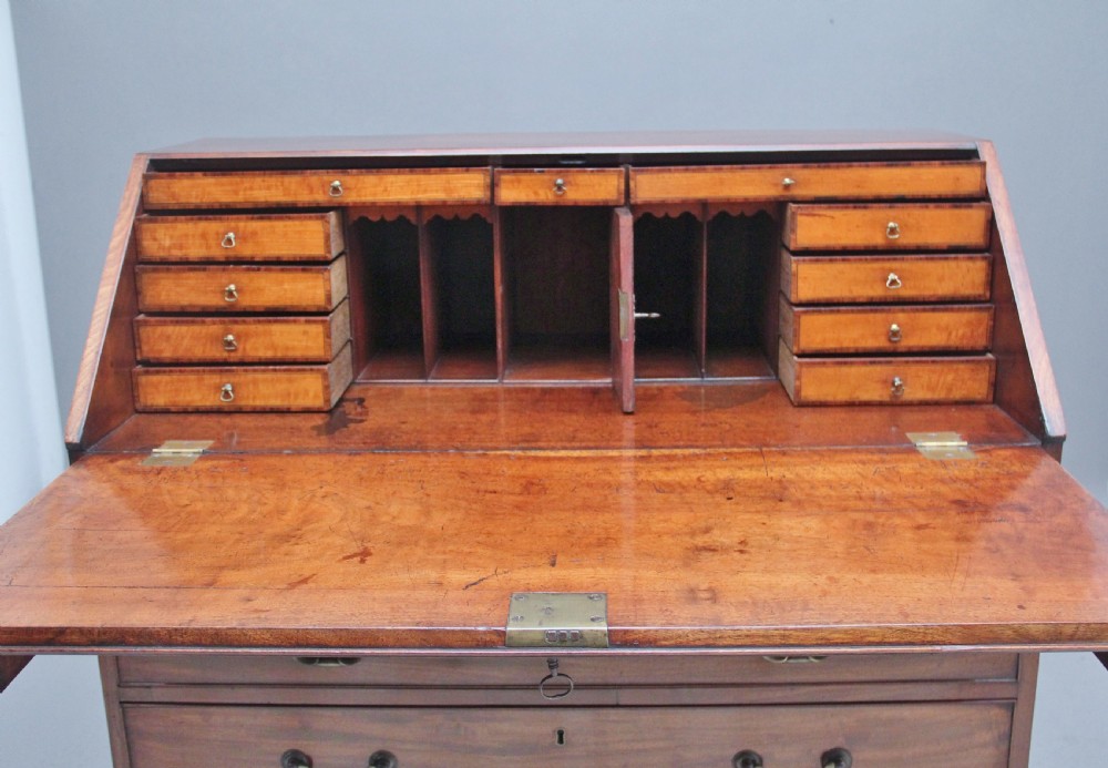 An eighteenth-century mahogany writing bureau featuring a slant-front slope above four graduated drawers with brass swan-neck handles and bracket feet. View XI
