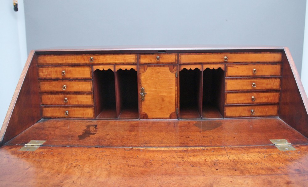 An eighteenth-century mahogany writing bureau featuring a slant-front slope above four graduated drawers with brass swan-neck handles and bracket feet. View XII