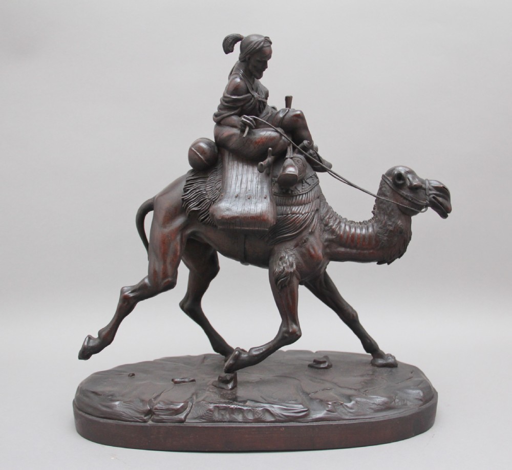 A 19th-century dark carved wood sculpture depicting a figure mounted on a striding camel upon an oval base. View III