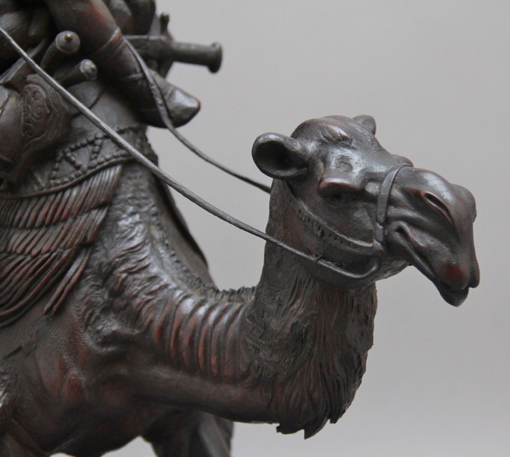 A 19th-century dark carved wood sculpture depicting a figure mounted on a striding camel upon an oval base. View VIII