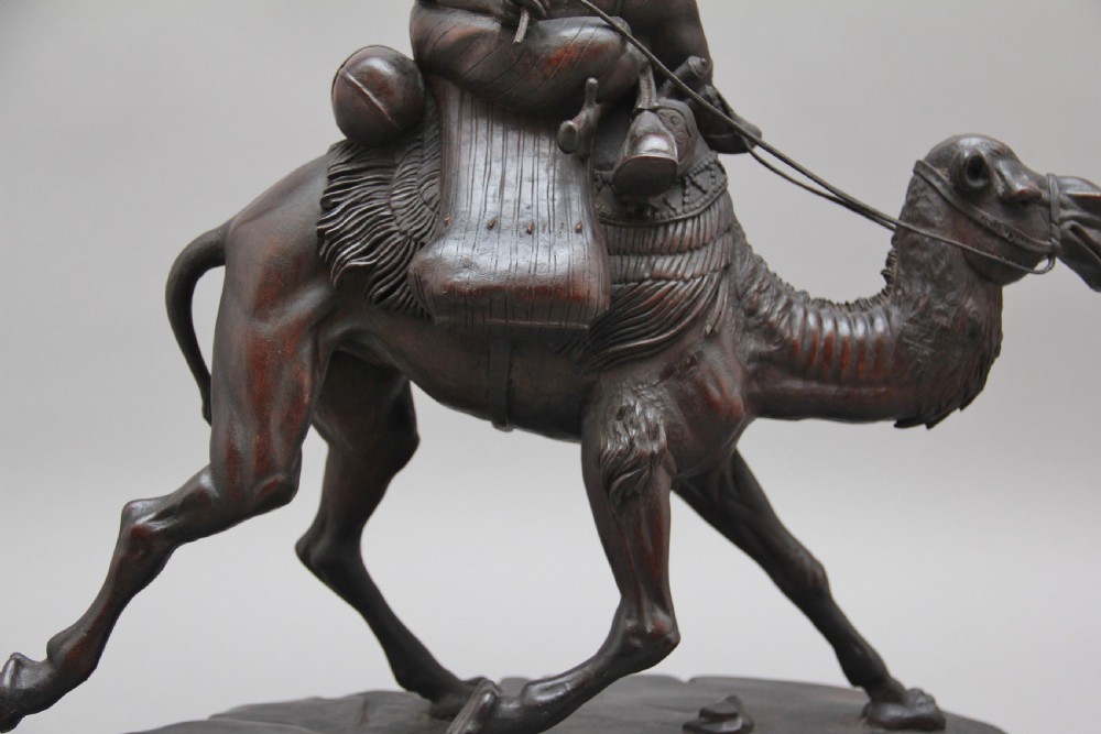 A 19th-century dark carved wood sculpture depicting a figure mounted on a striding camel upon an oval base. View IX