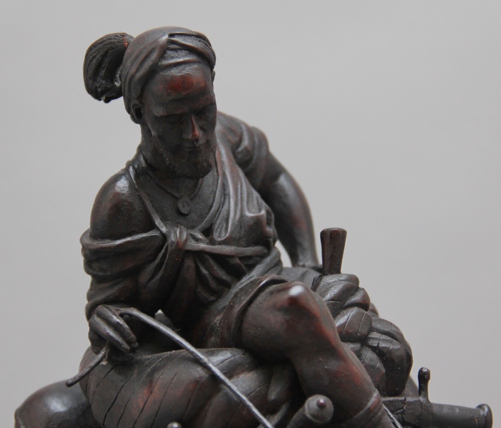 A 19th-century dark carved wood sculpture depicting a figure mounted on a striding camel upon an oval base. View X