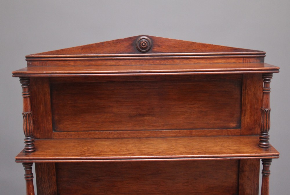 An early 19th-century oak bookcase featuring three open upper shelves topped with a pediment, above a lower cabinet with a brass grille door and spiral twist side columns. View V