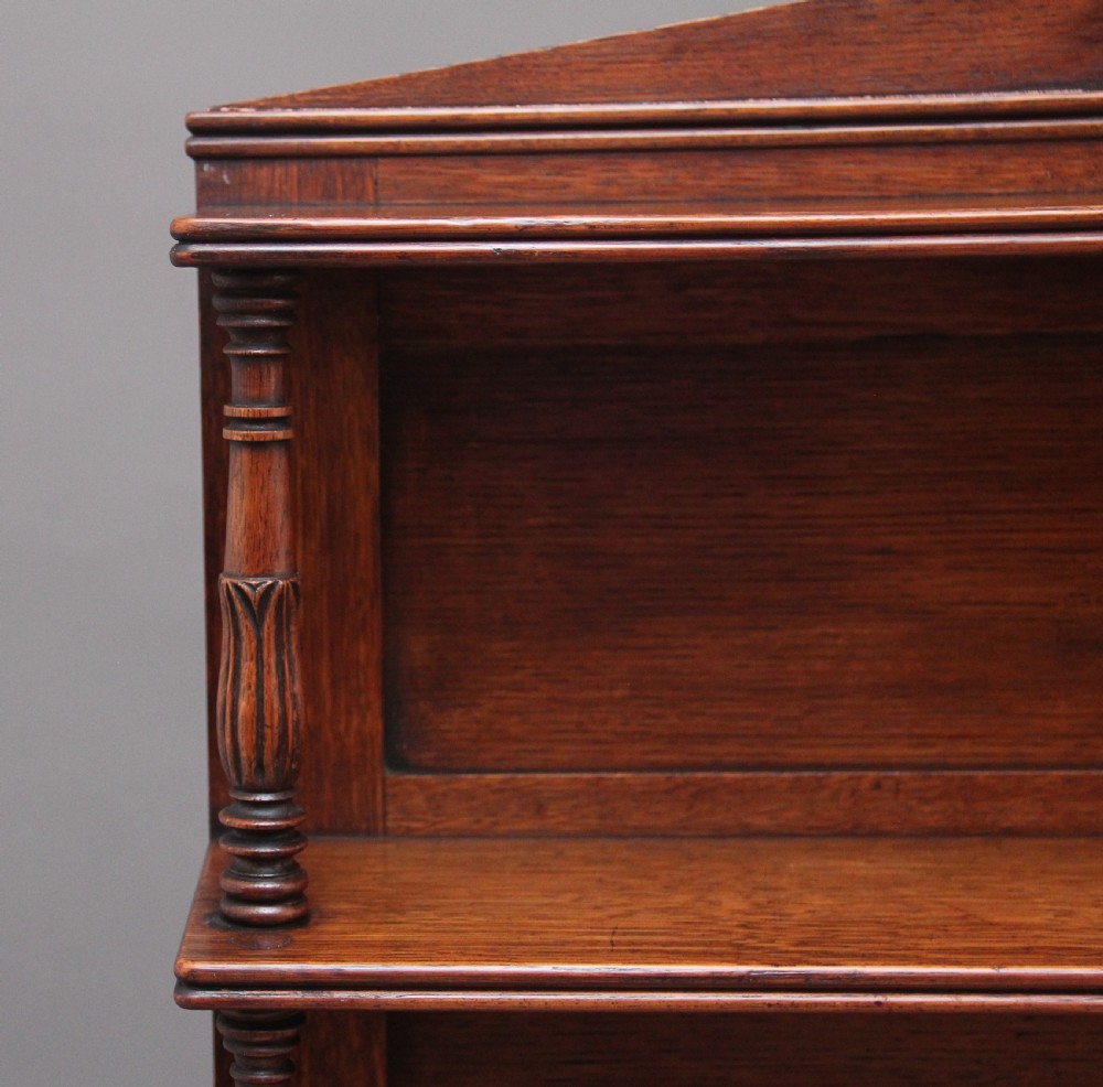 An early 19th-century oak bookcase featuring three open upper shelves topped with a pediment, above a lower cabinet with a brass grille door and spiral twist side columns. View VIII