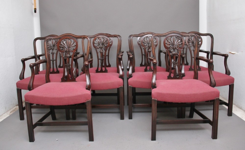A set of dark mahogany dining armchairs featuring intricate anthemion carved back splats, curved arms, and pink patterned upholstered seats. View II