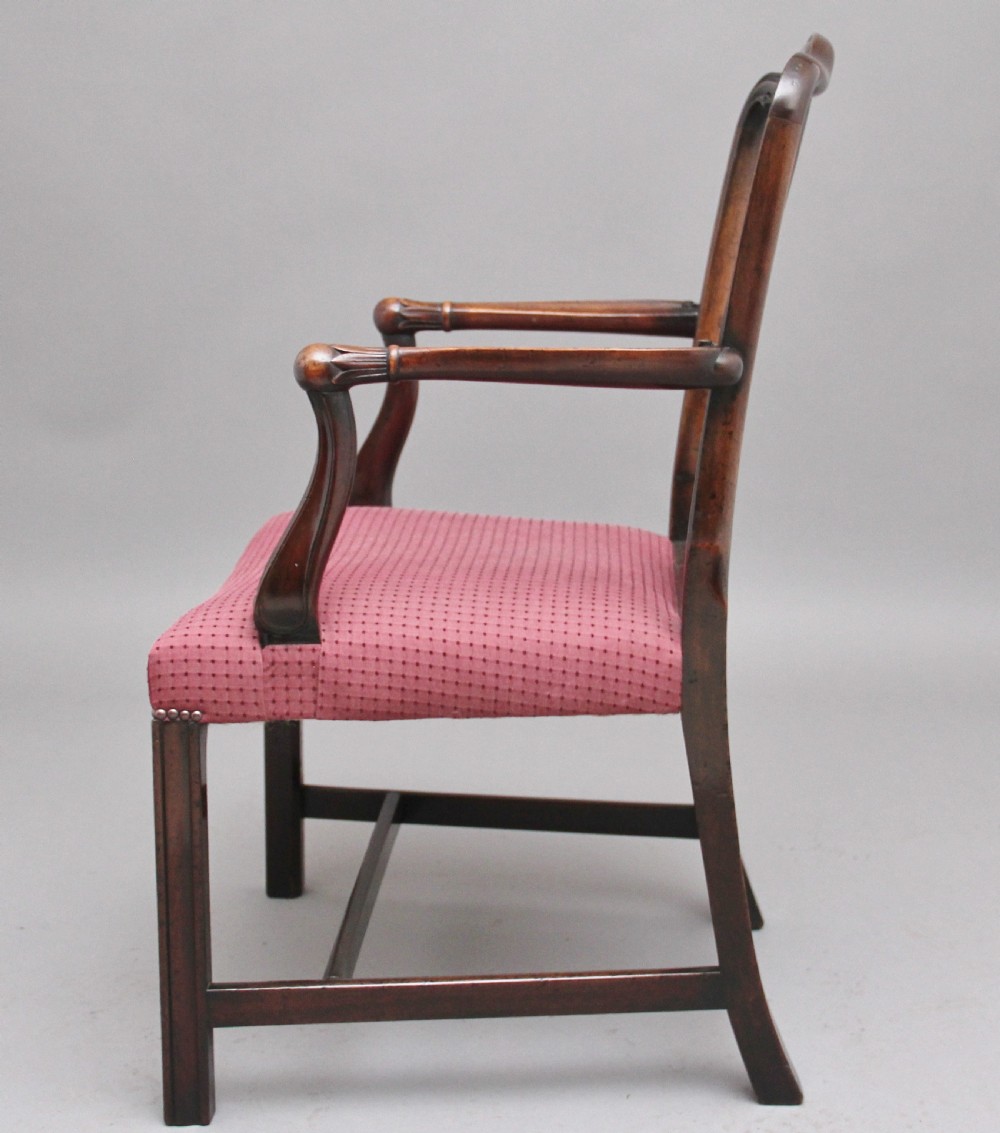 A set of dark mahogany dining armchairs featuring intricate anthemion carved back splats, curved arms, and pink patterned upholstered seats. View VI