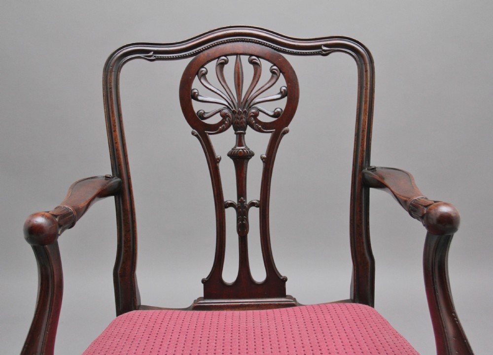 A set of dark mahogany dining armchairs featuring intricate anthemion carved back splats, curved arms, and pink patterned upholstered seats. View VII