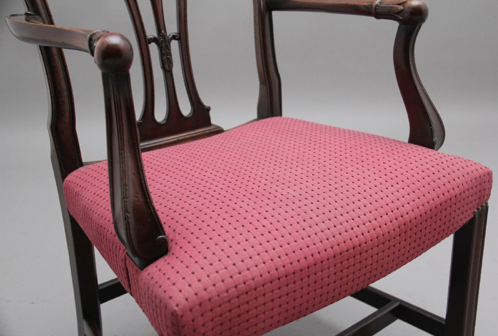 A set of dark mahogany dining armchairs featuring intricate anthemion carved back splats, curved arms, and pink patterned upholstered seats. View X