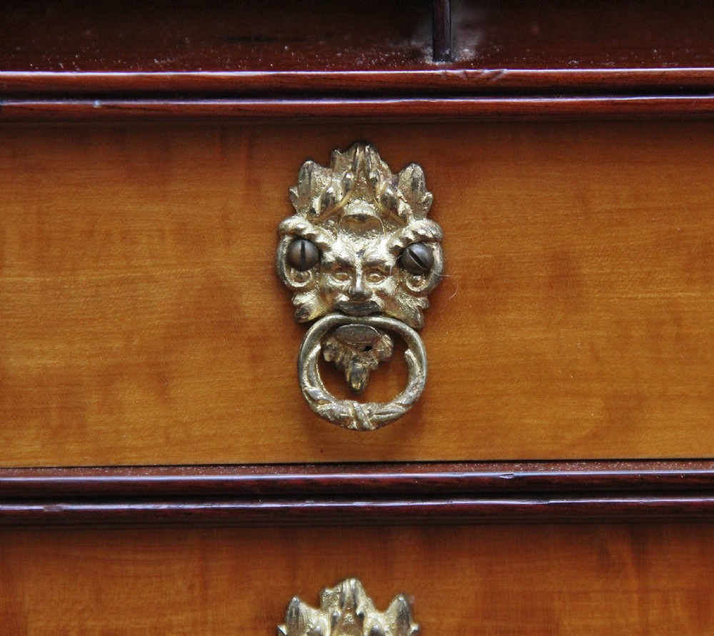 A 19th-century Sheraton revival satinwood writing desk featuring inlaid urn marquetry motifs, stepped side shelves, a central door compartment, and slender tapered legs. View VII