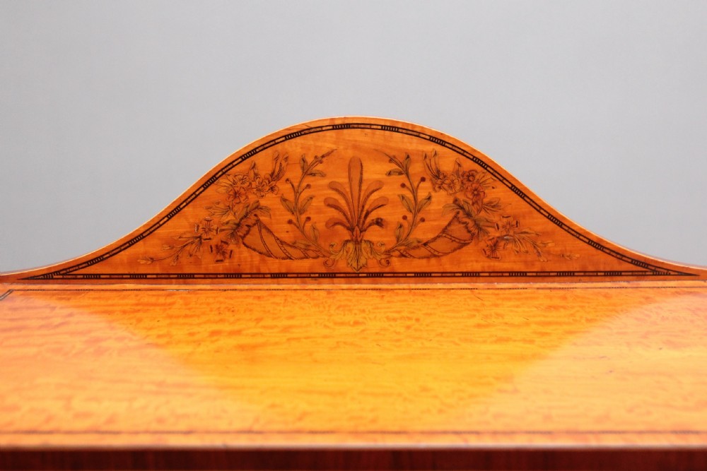 A 19th-century Sheraton revival satinwood writing desk featuring inlaid urn marquetry motifs, stepped side shelves, a central door compartment, and slender tapered legs. View XI