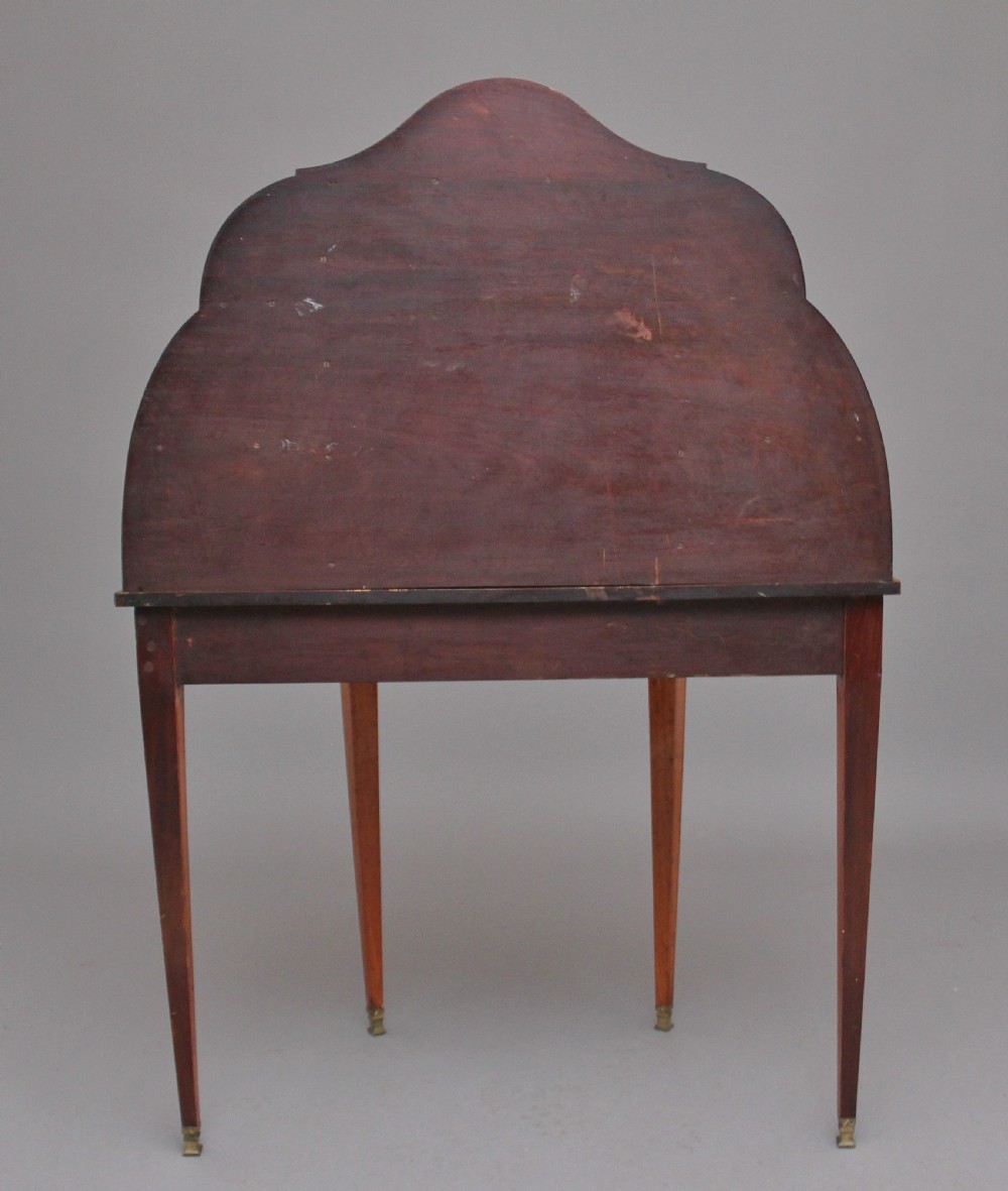 A 19th-century Sheraton revival satinwood writing desk featuring inlaid urn marquetry motifs, stepped side shelves, a central door compartment, and slender tapered legs. View XV