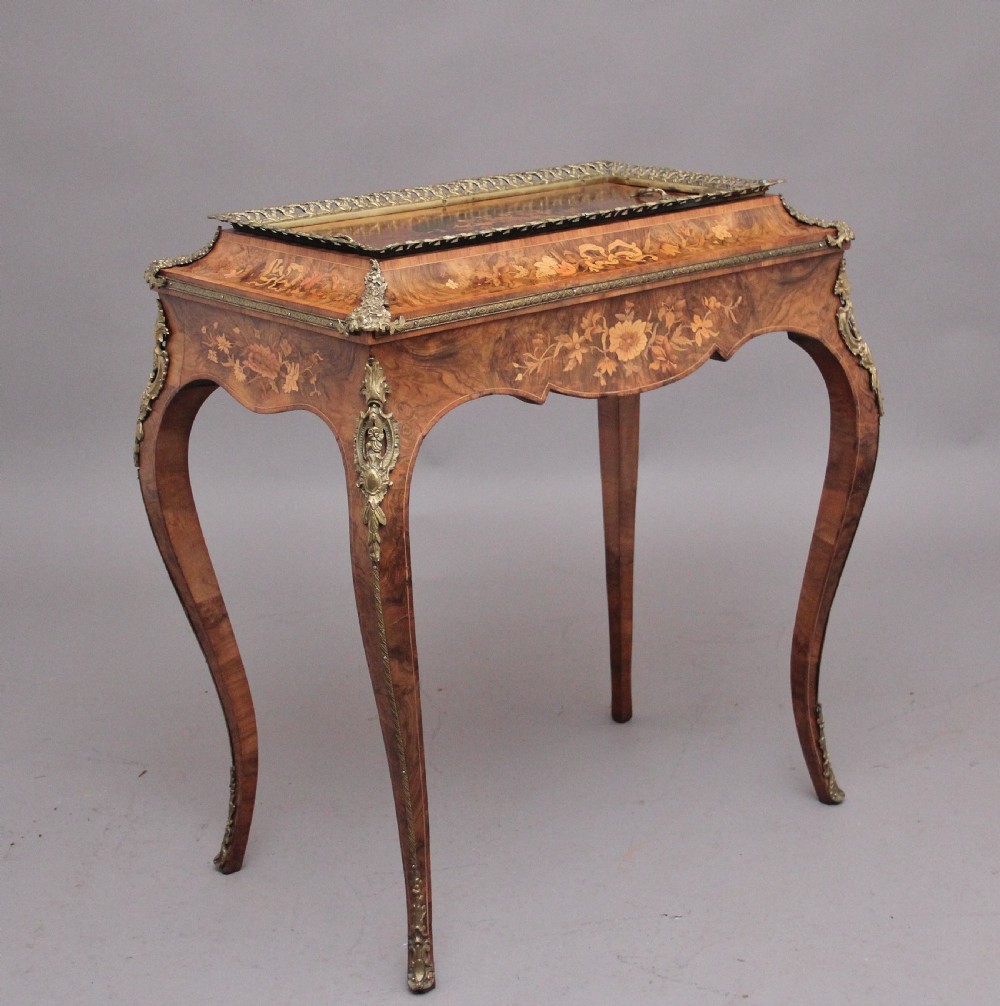A 19th-century French Louis XV style burr walnut jardiniere table with floral marquetry inlay, brass gallery top, and gilt bronze mounts on cabriole legs.