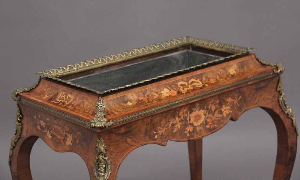 A 19th-century French Louis XV style burr walnut jardiniere table with floral marquetry inlay, brass gallery top, and gilt bronze mounts on cabriole legs. View V