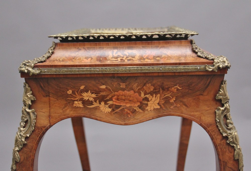 A 19th-century French Louis XV style burr walnut jardiniere table with floral marquetry inlay, brass gallery top, and gilt bronze mounts on cabriole legs. View X