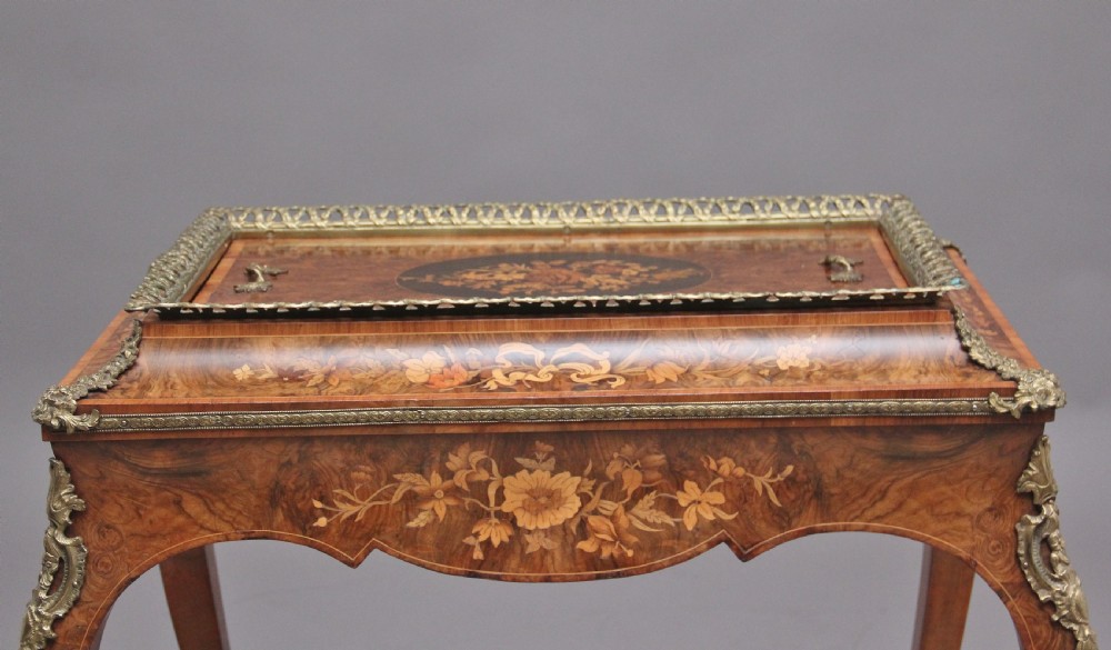 A 19th-century French Louis XV style burr walnut jardiniere table with floral marquetry inlay, brass gallery top, and gilt bronze mounts on cabriole legs. View XV