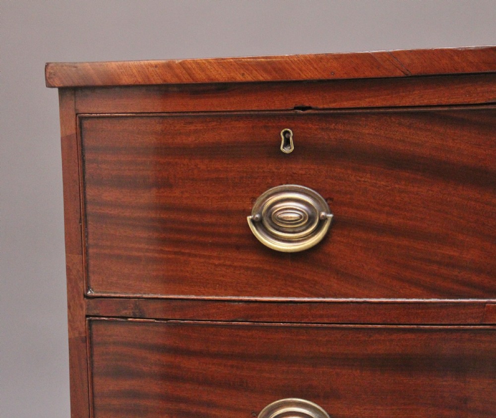 A 19th-century mahogany bowfront chest of drawers featuring two short drawers above two long drawers with oval brass handles and splayed bracket feet. View IV