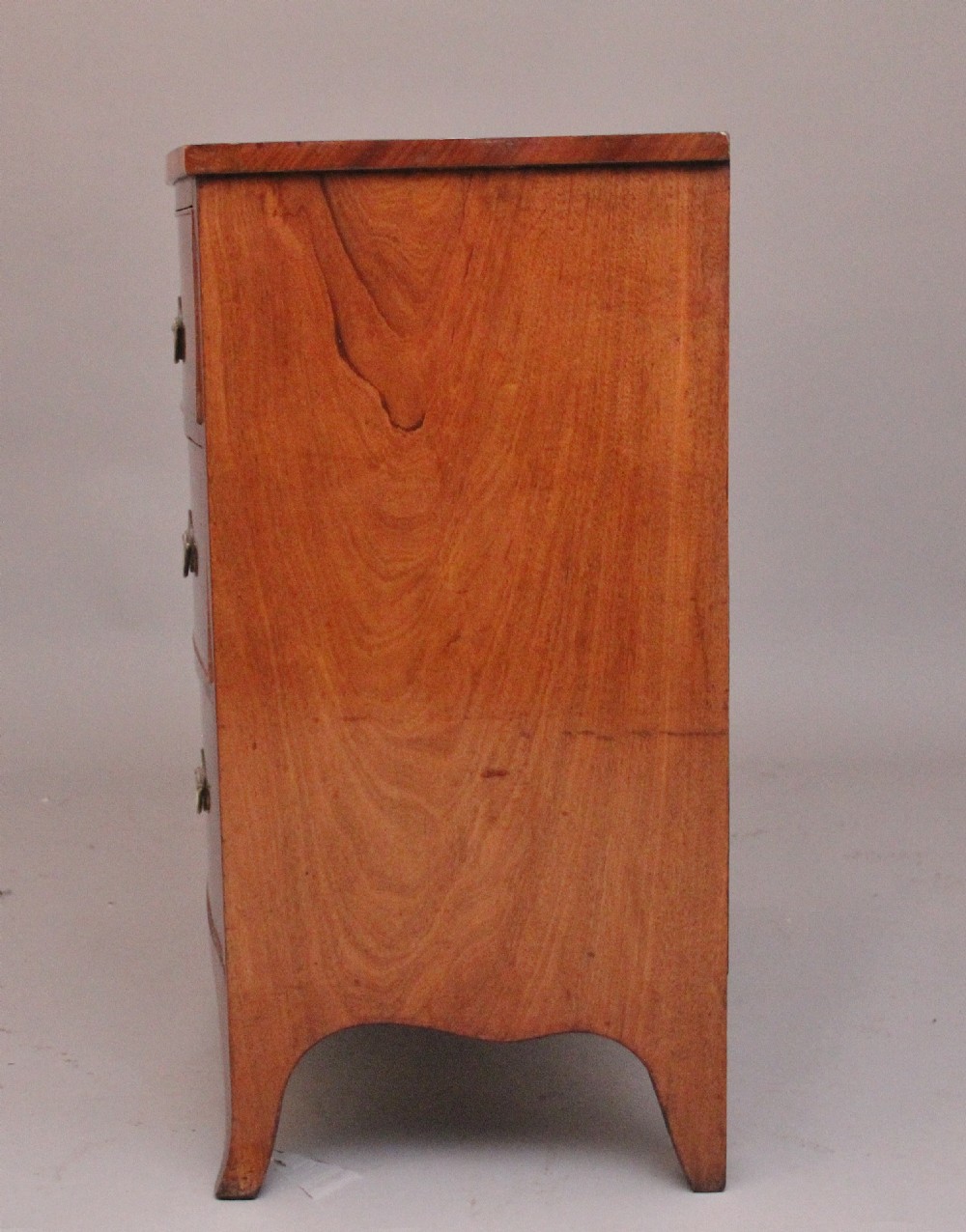 A 19th-century mahogany bowfront chest of drawers featuring two short drawers above two long drawers with oval brass handles and splayed bracket feet. View VI