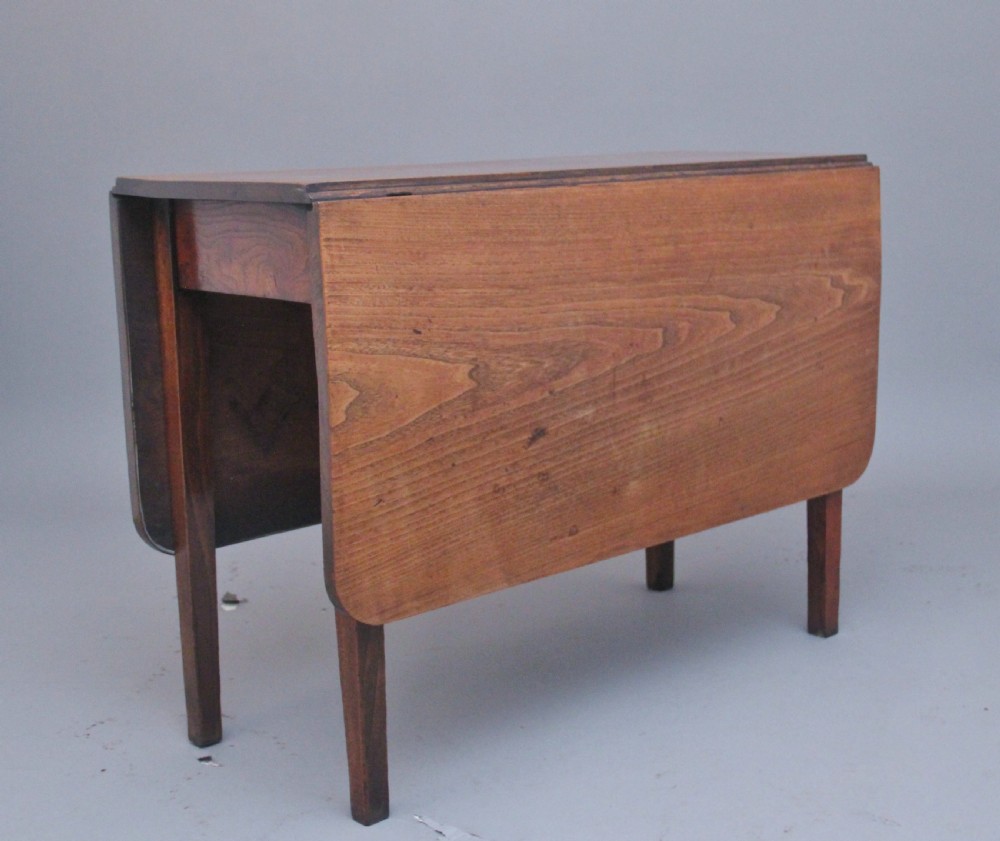 A 19th-century warm brown elm drop-leaf table featuring two hinged side flaps and straight wooden legs.
