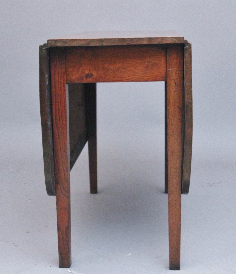 A 19th-century warm brown elm drop-leaf table featuring two hinged side flaps and straight wooden legs. View V