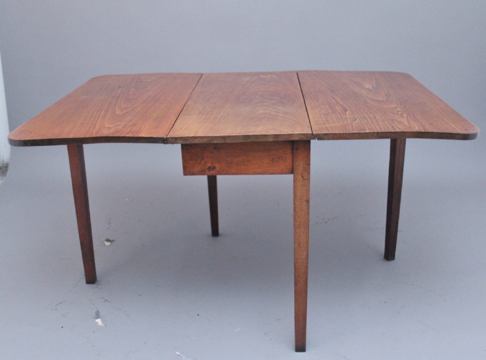 A 19th-century warm brown elm drop-leaf table featuring two hinged side flaps and straight wooden legs. View VI