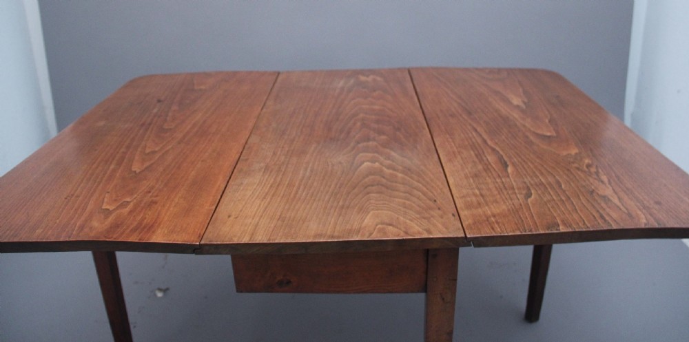 A 19th-century warm brown elm drop-leaf table featuring two hinged side flaps and straight wooden legs. View VII