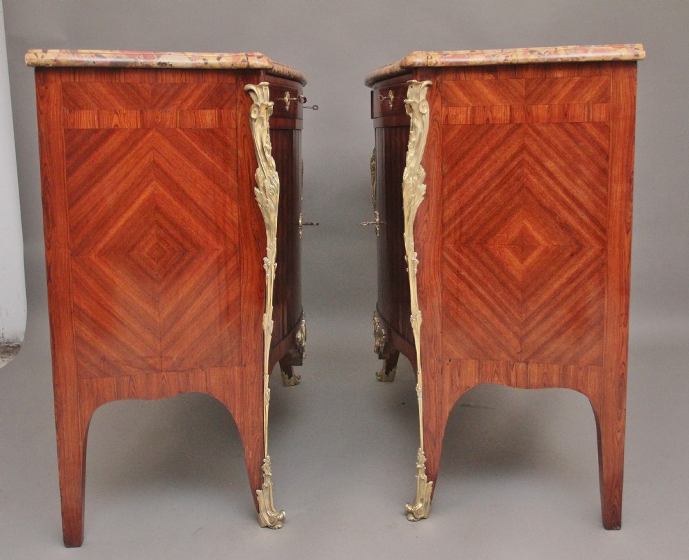 A matching pair of 19th-century French kingwood commodes featuring herringbone parquetry veneer, gilt bronze mounts, and fitted marble tops. View V