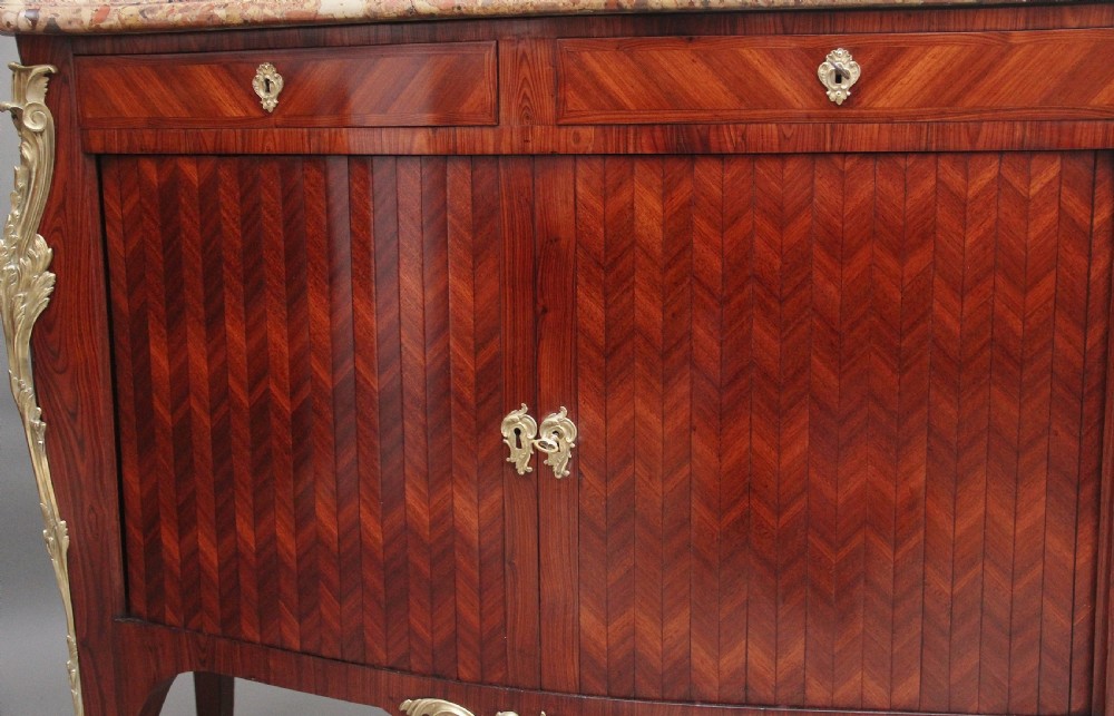 A matching pair of 19th-century French kingwood commodes featuring herringbone parquetry veneer, gilt bronze mounts, and fitted marble tops. View XII