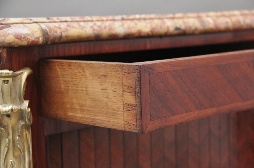 A matching pair of 19th-century French kingwood commodes featuring herringbone parquetry veneer, gilt bronze mounts, and fitted marble tops. View XVII