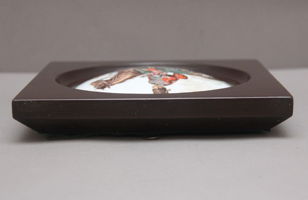 A square dark brown frame enclosing a circular white porcelain plaque depicting a military officer in uniform mounted on a brown horse. View IV