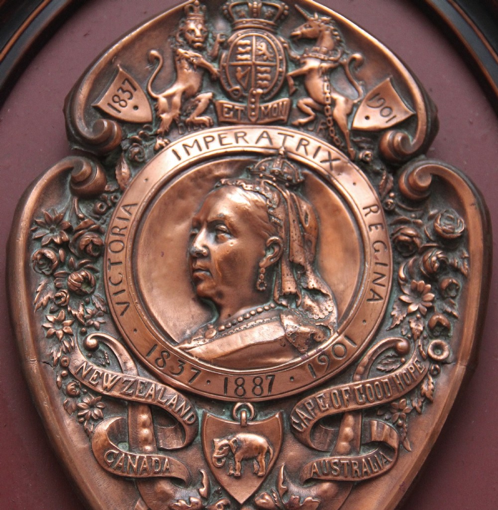 An oval framed copper plaque featuring a raised profile relief of Queen Victoria surrounded by British Royal heraldry and Commonwealth inscriptions. View II