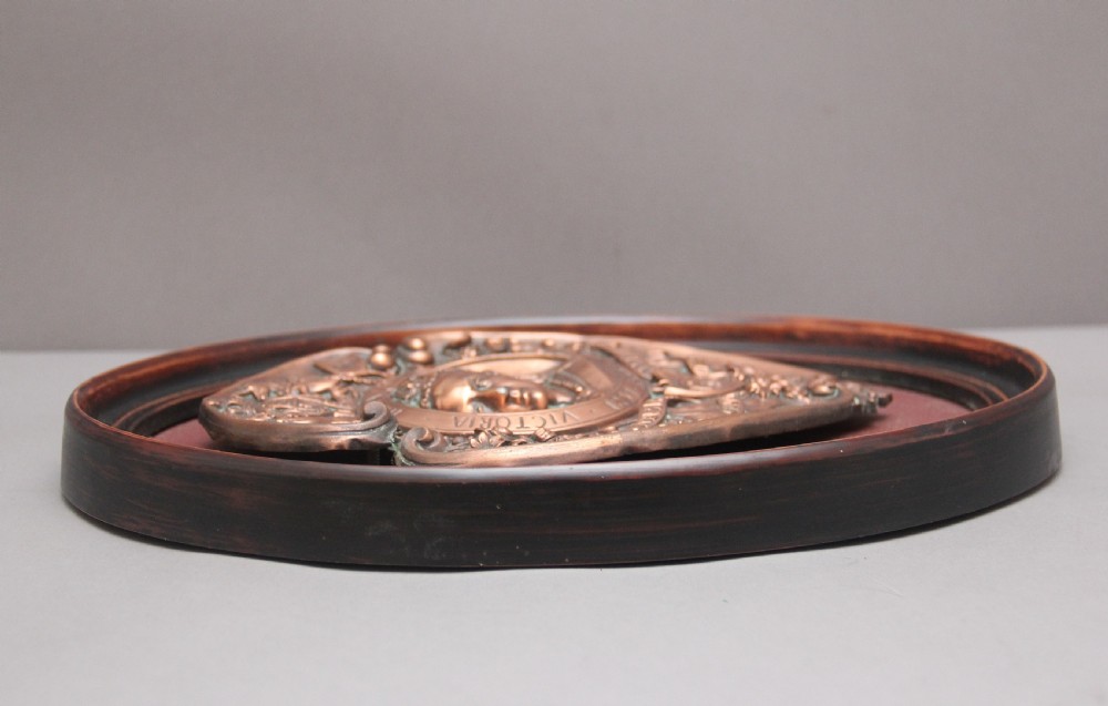 An oval framed copper plaque featuring a raised profile relief of Queen Victoria surrounded by British Royal heraldry and Commonwealth inscriptions. View IV